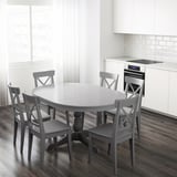 Bucătărie modernă cu masă extensibilă, scaune gri, frunze autodepozitare, dulapuri albe.