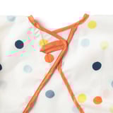 Prim-plan cu o salopetă colorată cu buline cu cravate portocalii strălucitoare și închidere cu cârlig, prezentând țesături și design de înaltă calitate.