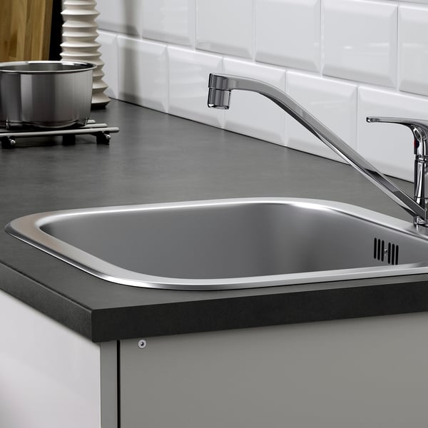 O chiuvetă modernă din oțel inoxidabil cu un robinet cromat cu arc înalt și un blat negru, parte a sistemului modular de bucătărie KNOXHULT.