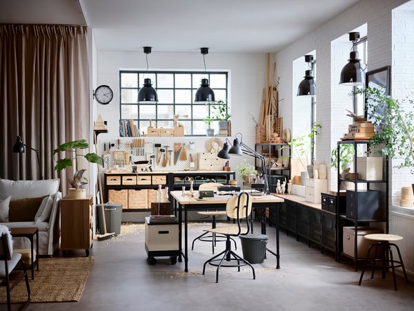 Atelier spațios cu birou KULLABERG, plante și lămpi negre, oferind un amestec de lemn natural și stil modern.