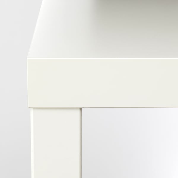 Colțul alb al unei măsuțe de cafea moderne, cu margini elegante și design minimalist.