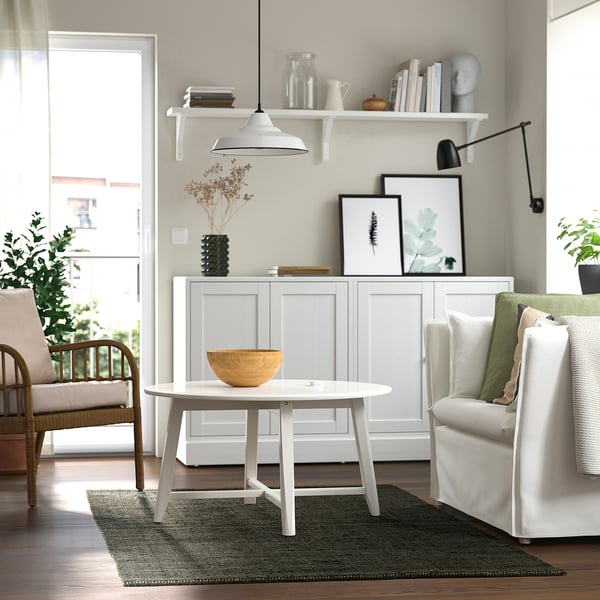 Living modern cu covor de iută LANDBANA, verde închis, mobilier alb, plante, tablouri, lumină suspendată.