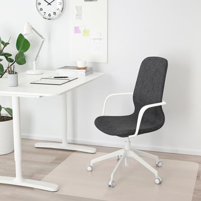 Birou minimalist modern cu scaun ergonomic negru LÅNGFJÄLL, birou alb, cărți, ceașcă, plantă, tablă albă și ceas.