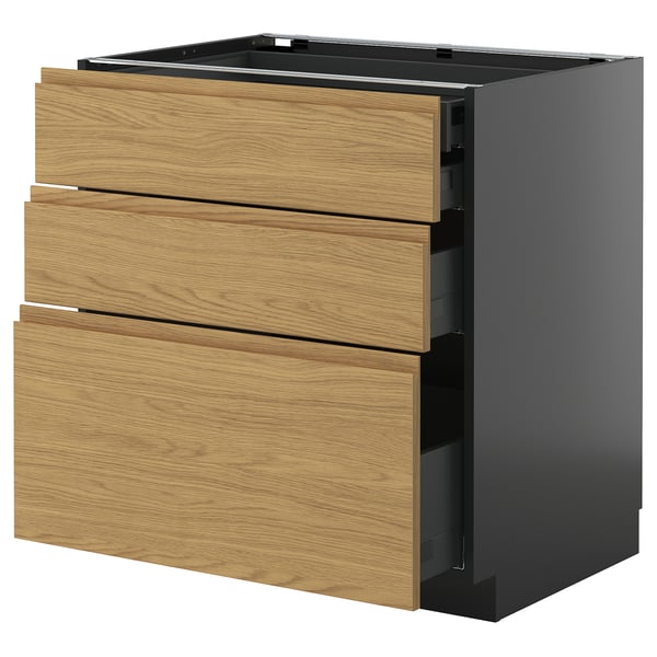 Un dulap de bucătărie modern cu trei sertare de culoare lemn, așezat pe un cadru gri închis. Designul este minimalist și minimal.