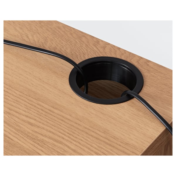 Birou din lemn cu sistem de gestionare a cablurilor, cu o priză rotundă și cabluri negre direcționate prin ea.