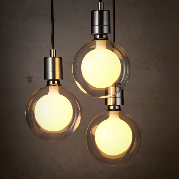 Trei becuri led sferice cu sticlă dublu strat agățate, emițând lumină caldă, dispuse într-o formațiune triunghiulară.