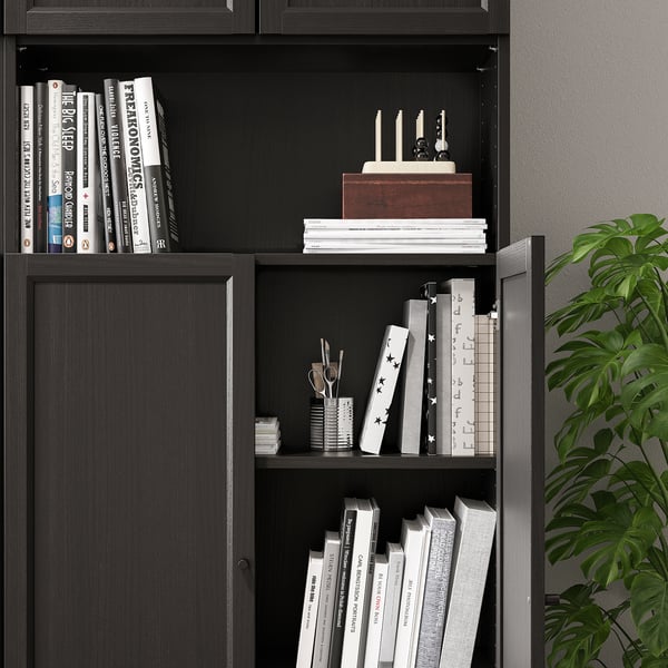 Bibliotecă neagră cu panouri reglabile pentru uși, care adăpostește diverse cărți și obiecte decorative.