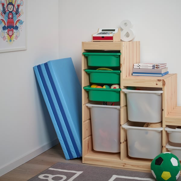 Zonă de joacă pentru copii cu covoraș albastru PLUFSIG pentru exersarea mișcărilor de gimnastică, coșuri de depozitare din lemn cu jucării și decor colorat.