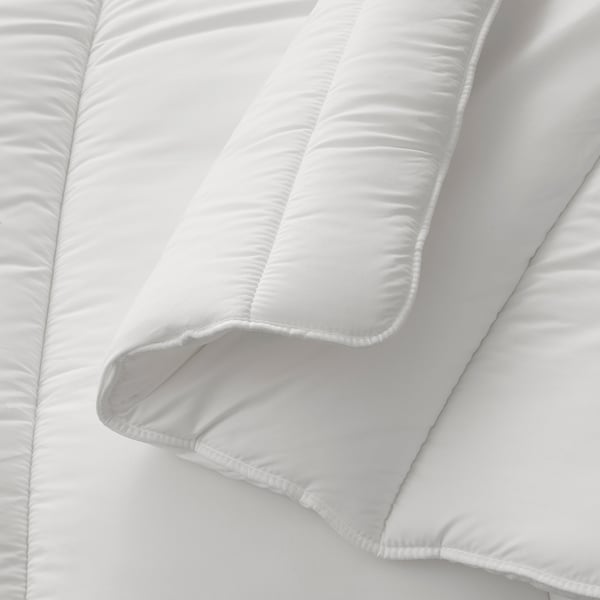 Prim-plan cu o plapumă moale, albă, matlasată, care prezintă cusături fine și material de pluș.
