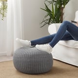 Persoana se relaxează pe picioarele albe secționale, sprijinindu-se pe puful SANDARED tricotat gri, care servește ca un taburet.