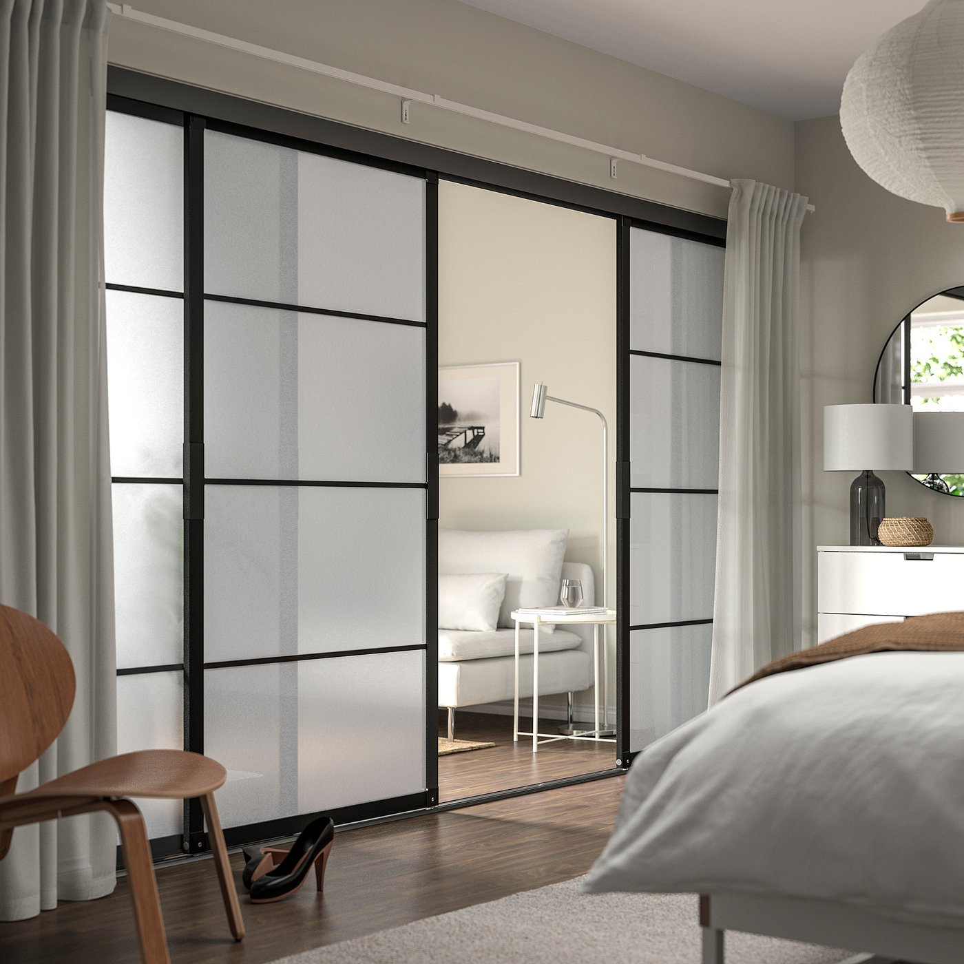 Dormitor modern: uși de dulap din sticlă SKYTTA, rame negre, perdele gri, mobilier din lemn, lenjerie de pat albă, scaun din lemn, panouri mate.
