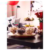 Tavă de servire din lemn SNUDDA cu nuci. Rotund, maro, conține trei boluri de sticlă. Piesă centrală înaltă cu trandafiri roșii. Aranjarea mesei negre.