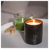 Două lumânări aprinse pe o masă: una verde, una neagră cu flacără strălucitoare, emițând un parfum proaspăt de matcha verde, ghimbir și citrice.