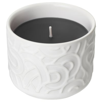 Expune o lumânare parfumată albă SÖTRÖNN într-un borcan de ceramică cu un design texturat, ondulat. Lumânarea este aprinsă, cu un fitil de bumbac în centru.