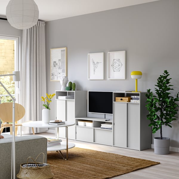 Living modern cu televizor gri SPIKSMED, televizor cu ecran plat, plantă, decor, flori galbene, coș de răchită, artă abstractă, perdele luminoase.