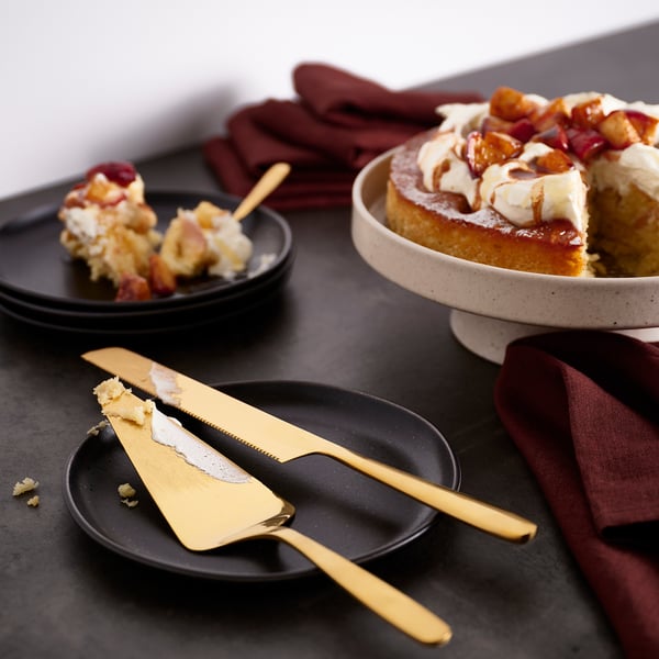 Felie de tort Golden TILLAGD și cuțit pe masă, cu desert parțial feliat. Feliați mare, sprijinindu-se pe o farfurie întunecată, cuțitul lung.