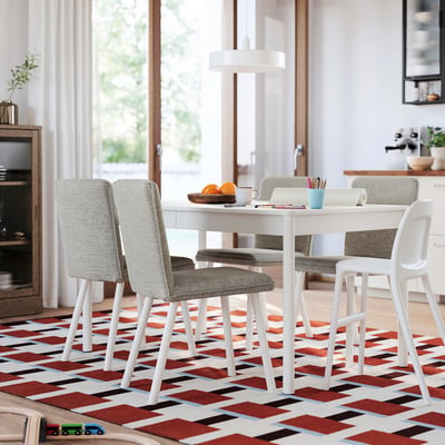 Zona de dining moderna cu masa extensibila, scaune cu perne, covor geometric, planta, ferestre deschise.