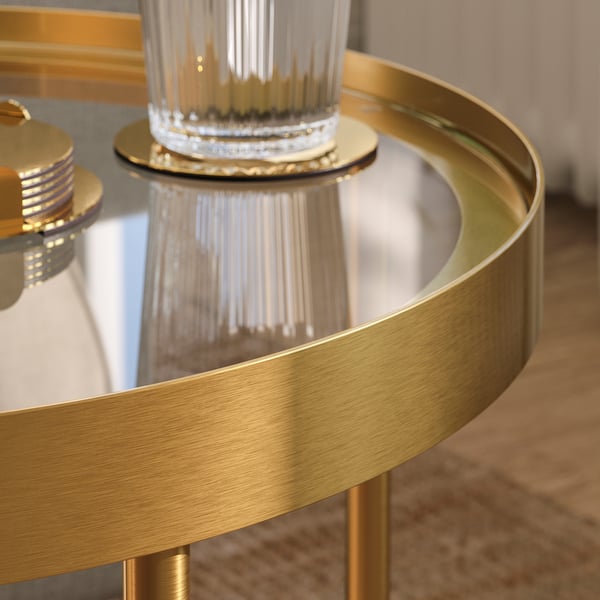 Masă laterală elegantă din metal auriu, cu blat din sticlă transparentă, care prezintă măiestrie rafinată și design de calitate.