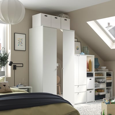 Dormitor modern cu depozitare albă VIHALS, pat, lenjerie de pat verde/neagră, luminator, artă, accesorii.