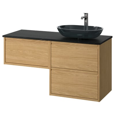 Modern oak bathroom vanity with black countertop and glass basin. Three drawers and sleek, minimalist design.