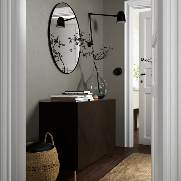 Modern entryway with dark cabinet, mirror, and decor.