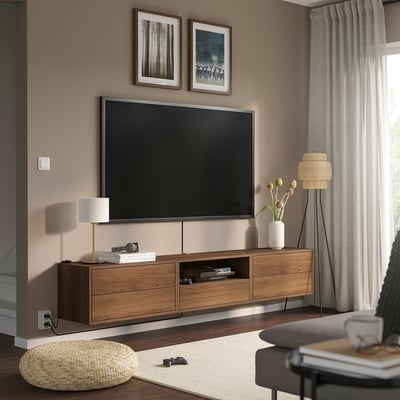 Modern living room with wall-mounted tv on EKET unit. Wooden drawers, shelves, and accessories. Light curtains, rug, and cushions.