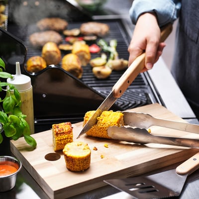 Person grilling vegetables with a knife. GRILLTIDER tool set helps with grilling.