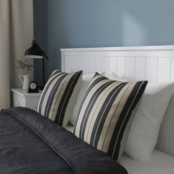 Image shows a bed with striped pillows and drawers on castors for storage under the bed.