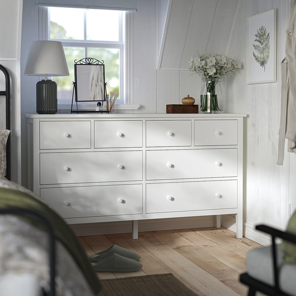 White dresser with vase, mirror, lamp, slippers. Bedroom decor.