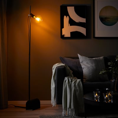 Cosy living room with HÅRSLINGA black floor lamp, couch, and candles.