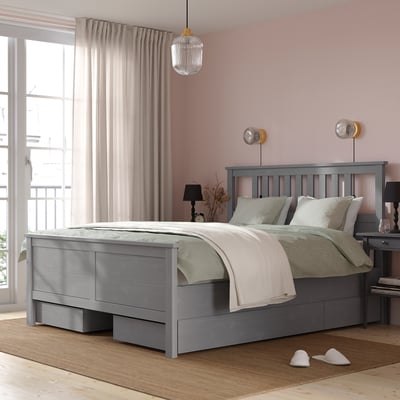Minimalist grey HEMNES bed with slatted base and storage, positioned large near window with light curtains.