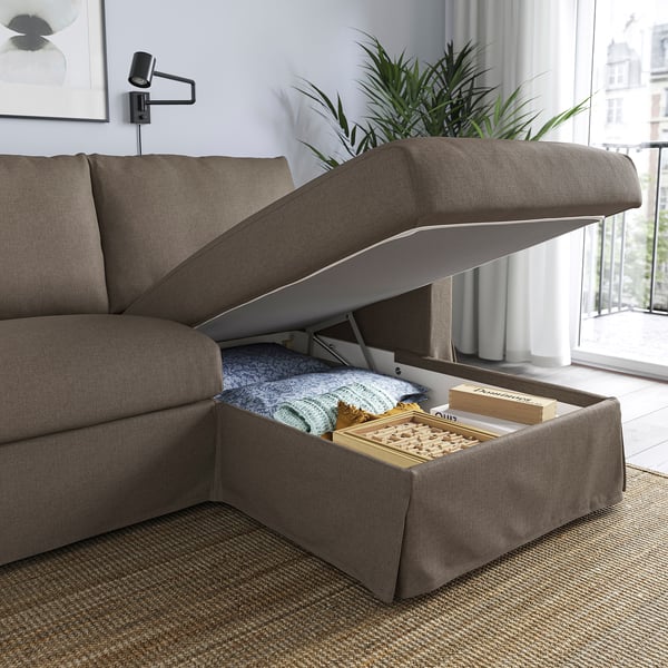Modern sofa with chaise, showcasing storage under the seat filled with blankets and board games.