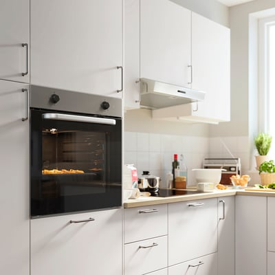 Modern kitchen featuring sleek black LAGAN oven in white cabinets, surrounded by white countertops and essentials.
