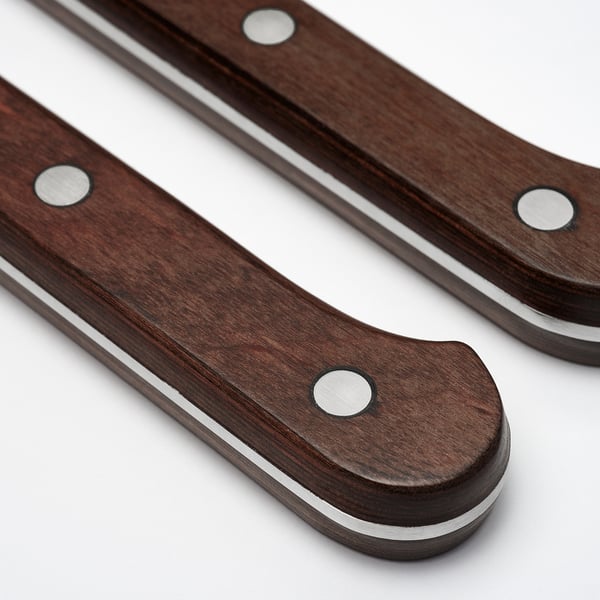Two steak knives with dark, polished wooden handles and stainless steel blades, featuring a serrated edge for smooth cutting.