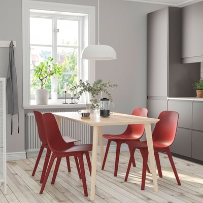 Small modern dining set with light wood table and red chairs, designed for cosy spaces.