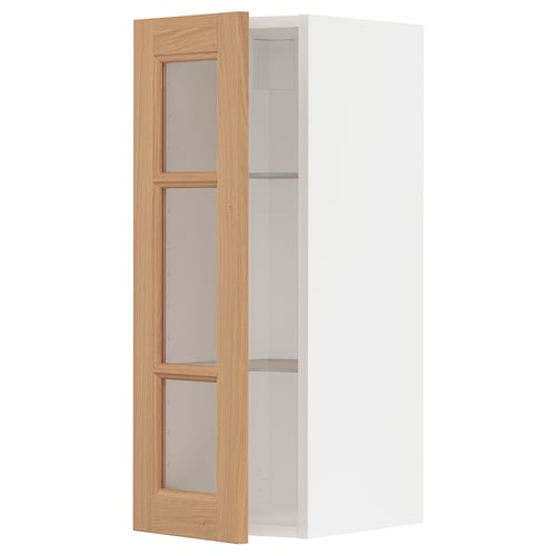 An open METOD kitchen cabinet with oak doors. The cabinet is white and has three glass shelves.