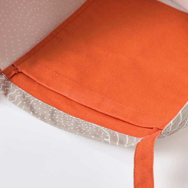 A close-up of an orange fabric item with neat stitching and patterned edges.