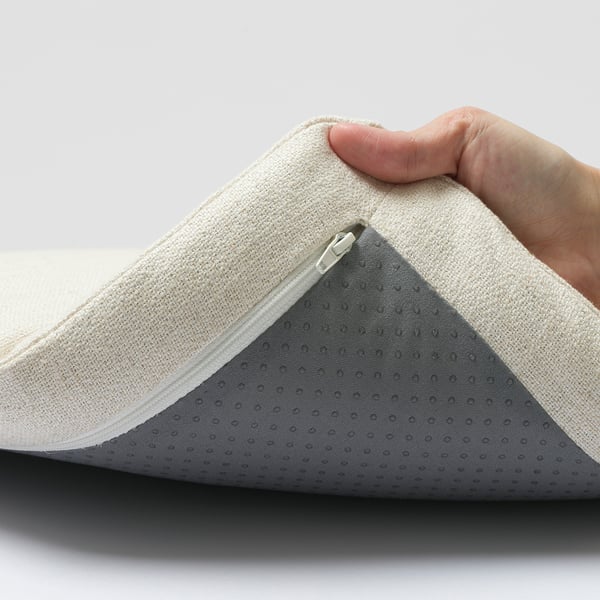 A hand holding open an armchair cushion, showing zip and fabric layers.