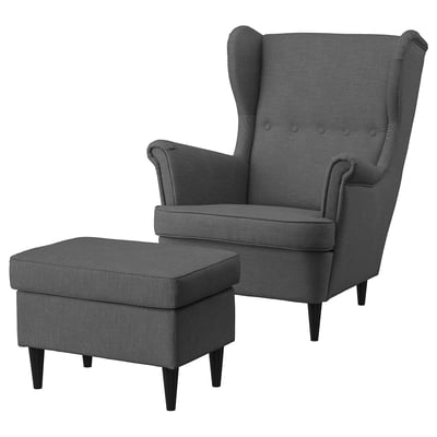 Dark grey fabric wing chair with matching ottoman, high back, button tufting, wooden legs.
