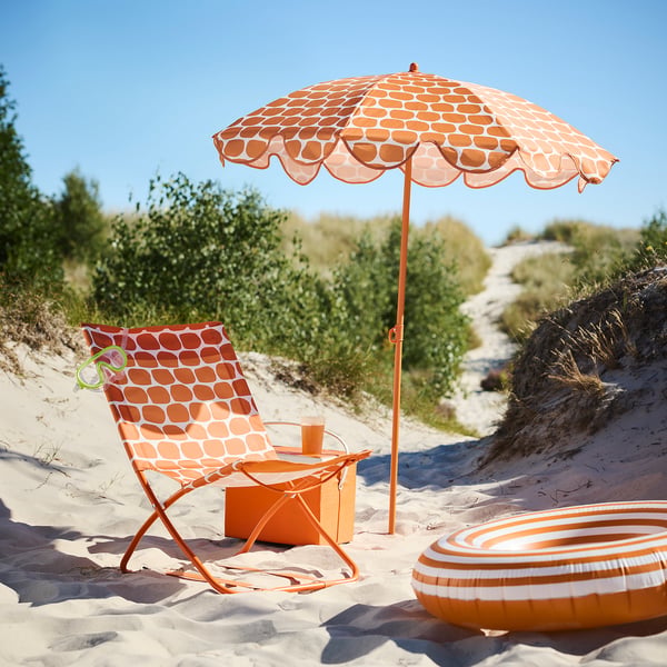 STRANDÖN orange-patterned foldable beach chair and umbrella, made of polyester and steel, perfectly sized for beach or park relaxation.