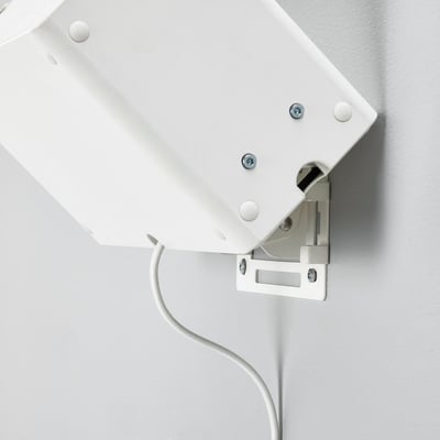 White wall-mount bracket for speaker, securely fixed with screws, connected by a cable.