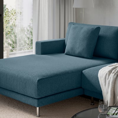 Modern blue sectional sofa with clean lines, plush cushions, and metallic legs, positioned near a large window with curtains.