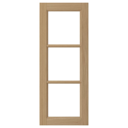 A VEDHAMN kitchen cabinet door in natural oak wood with glass panels framed by solid oak.