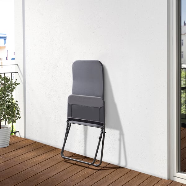 Foldable grey chair leaning against white wall. Ideal for outdoor relaxation.