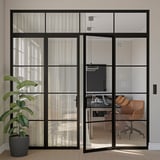 Modern office with glass doors, sheer curtains, leather chairs, plant.