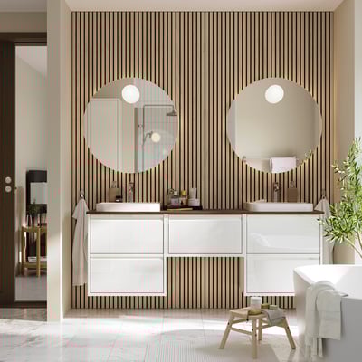 Modern bathroom with white ÄNGSJÖN vanity, dual sinks, mirrors, and bold wallpaper.