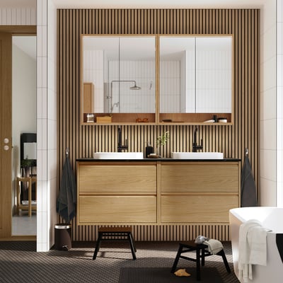 Modern bathroom with light wood ÄNGSJÖN vanity, dual sinks, wooden backdrop, large mirrors, and towel racks.