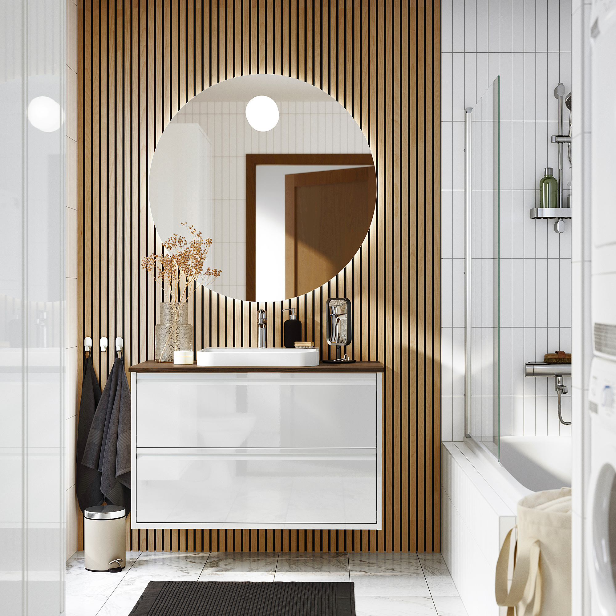 Modern bathroom with ÄNGSJÖN glossy cabinet, marble sink, mirror, wooden slats, black rug, and glass shower.