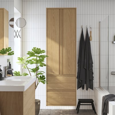 Modern bathroom with ÄNGSJÖN cabinet, towels, shower, and plant.