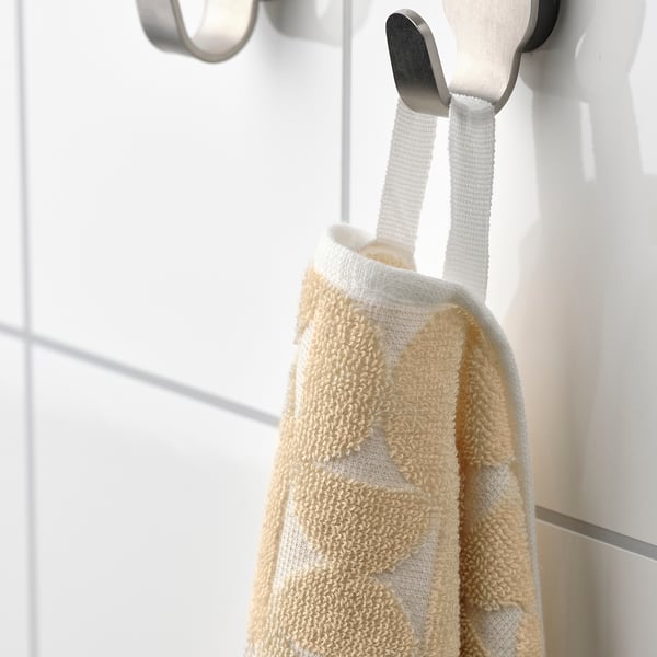 Beige towel with textured pattern hangs on silver hook, soft and absorbent.